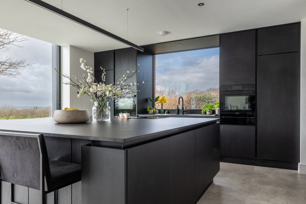 bespoke kitchen in essex showing a dark grey modern kitchen with an island and white quartz top